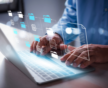 Person typing on laptop with document icons above it